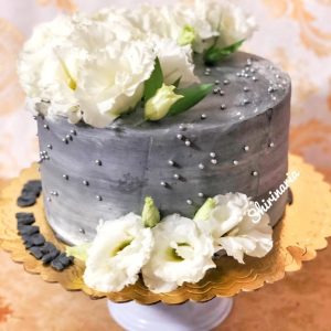 کیک تولد خاکستری با گلهای سفید
